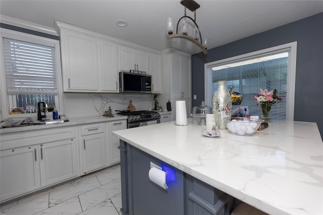 kitchen featuring sink, hanging light fixtures, tasteful backsplash, light stone counters, and appliances with stainless steel finishes