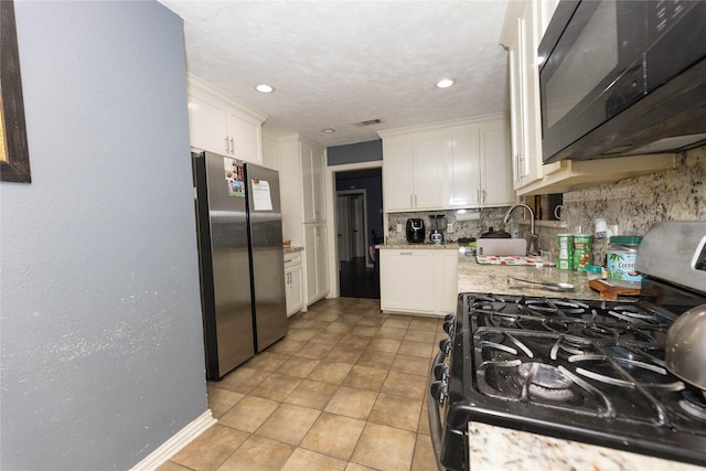 kitchen with white cabinets, sink, decorative backsplash, black range with gas cooktop, and stainless steel refrigerator