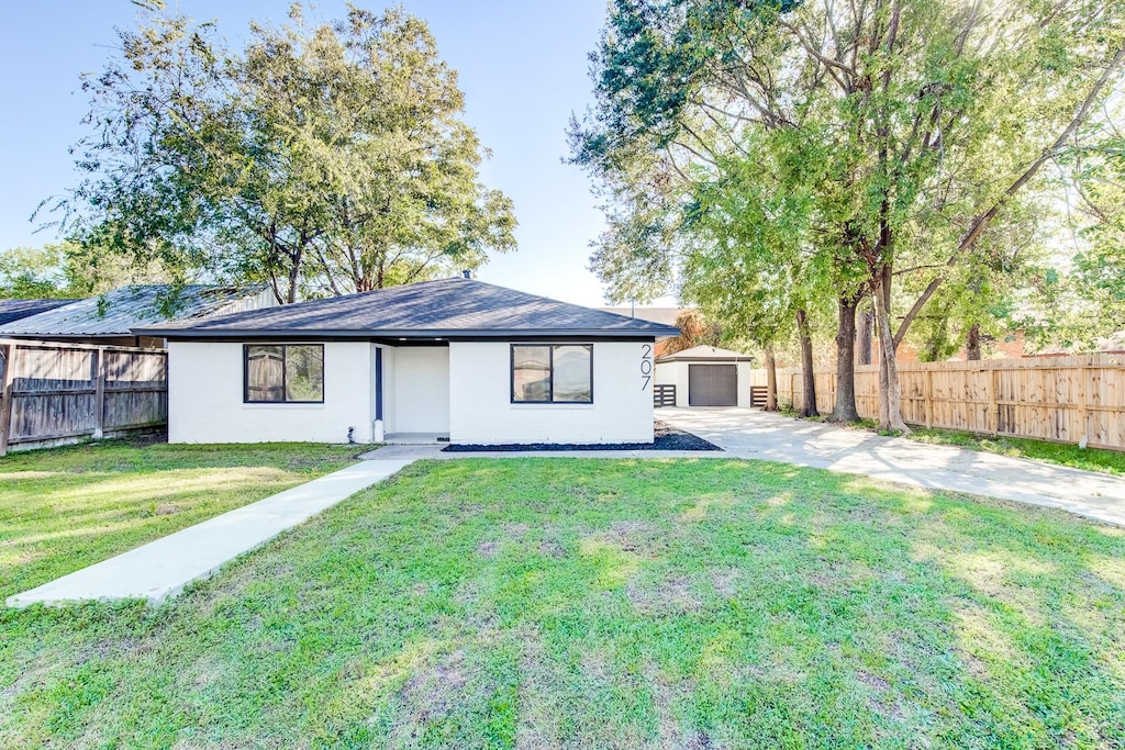 rear view of house featuring a garage, an outdoor structure, and a yard