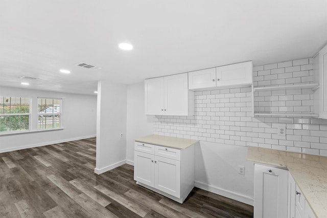 kitchen with white cabinets, light stone counters, backsplash, and dark wood-type flooring