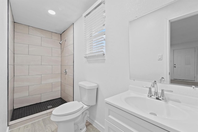 bathroom with tiled shower, vanity, and toilet