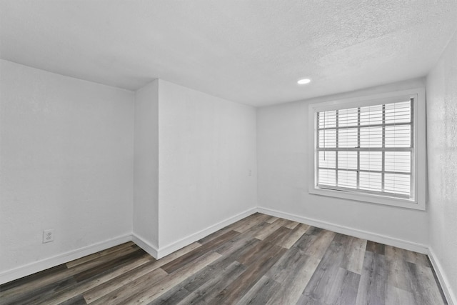 spare room with a textured ceiling and dark wood-type flooring