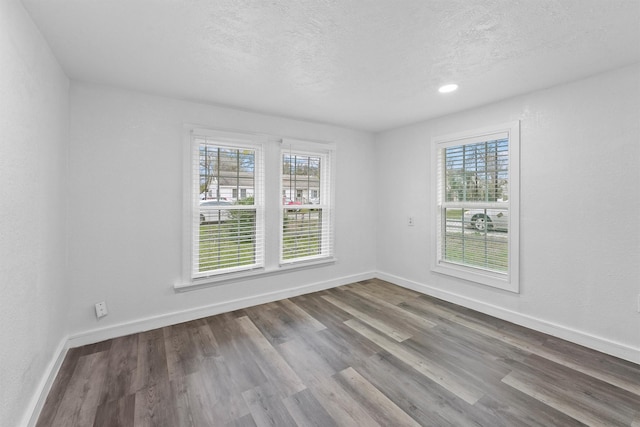 unfurnished room featuring wood-type flooring, a textured ceiling, and a wealth of natural light