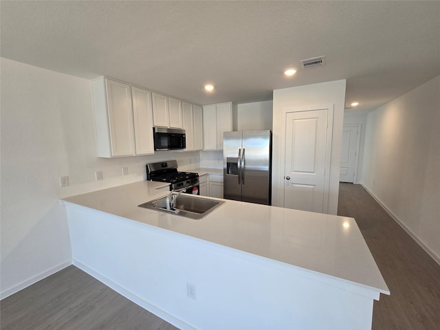 kitchen with white cabinetry, sink, dark wood-type flooring, stainless steel appliances, and kitchen peninsula