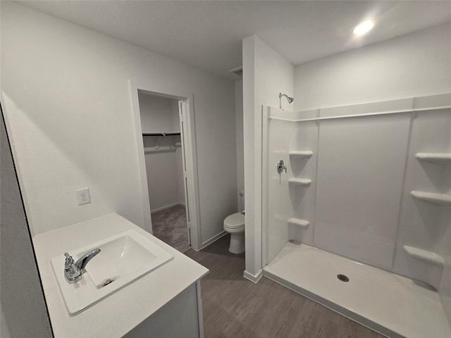 bathroom with hardwood / wood-style flooring, vanity, toilet, and walk in shower