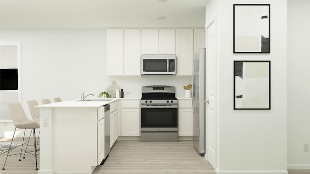 kitchen featuring kitchen peninsula, a kitchen breakfast bar, stainless steel appliances, sink, and white cabinets