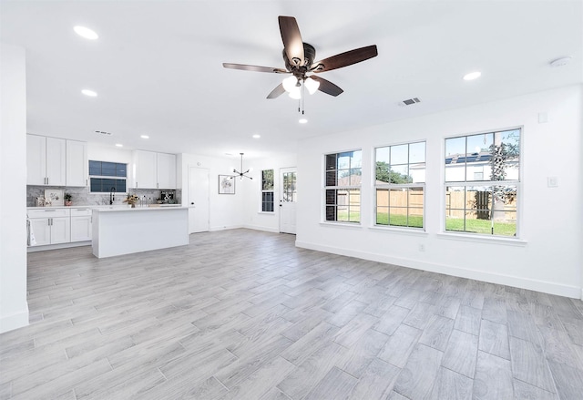 unfurnished living room with ceiling fan, light hardwood / wood-style floors, and sink