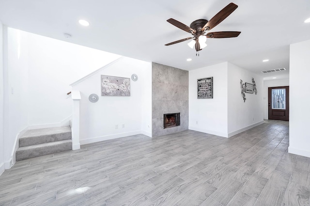 unfurnished living room with ceiling fan, a fireplace, and light hardwood / wood-style floors