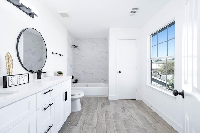 full bathroom with vanity, tiled shower / bath combo, and toilet