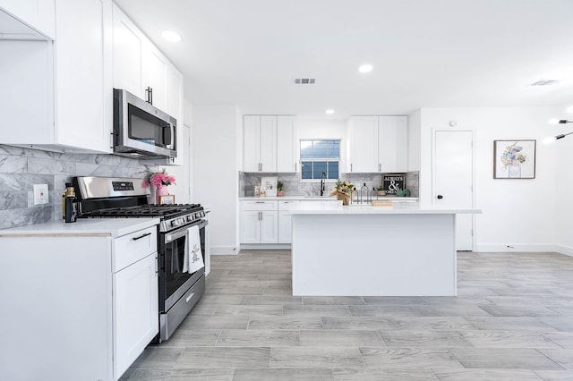 kitchen with a center island, white cabinets, stainless steel appliances, and sink