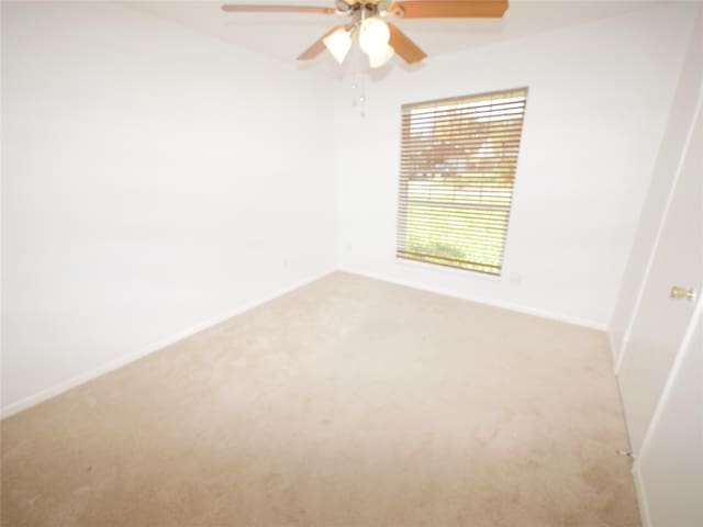 carpeted spare room featuring ceiling fan