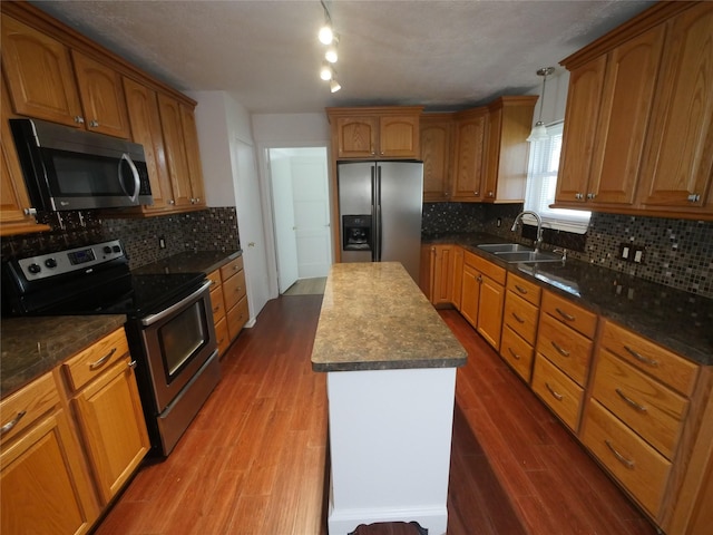 kitchen with sink, decorative light fixtures, dark wood-type flooring, and stainless steel appliances