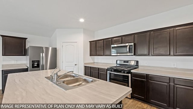 kitchen with sink, an island with sink, dark brown cabinets, appliances with stainless steel finishes, and light wood-type flooring