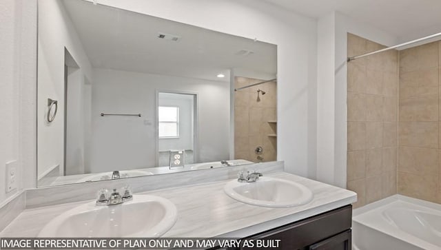 bathroom with tiled shower / bath combo and vanity