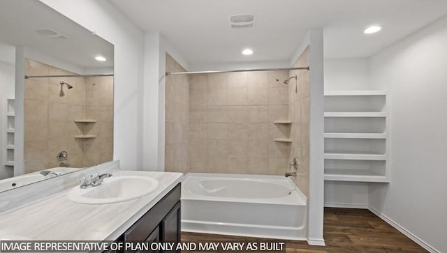 bathroom with hardwood / wood-style floors, vanity, and tiled shower / bath combo