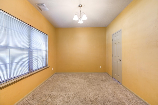 empty room with light carpet and an inviting chandelier