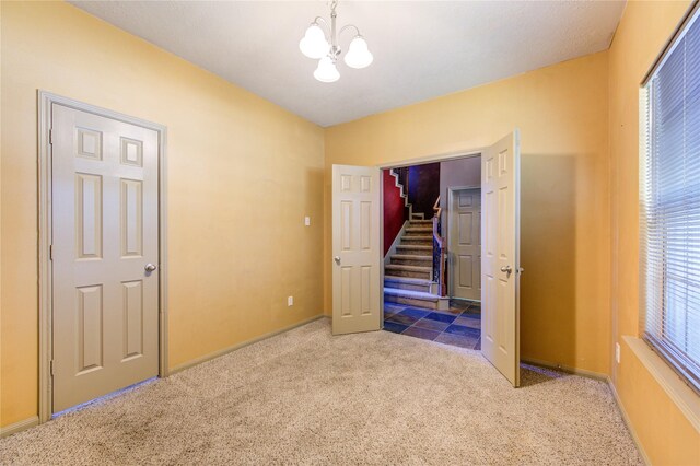 unfurnished bedroom with an inviting chandelier and carpet floors