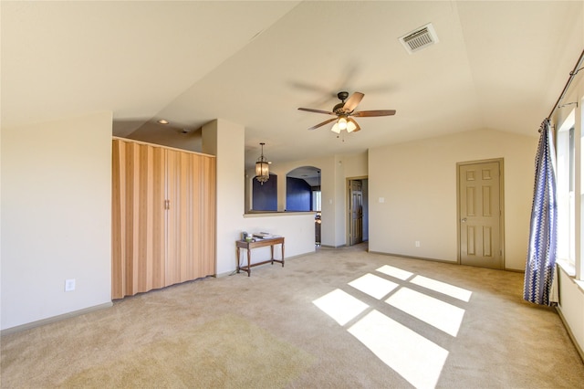 unfurnished living room with ceiling fan, light colored carpet, and lofted ceiling