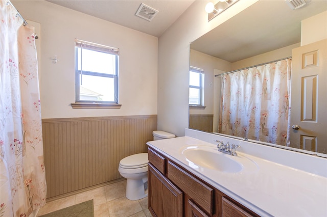 bathroom featuring toilet, vanity, tile patterned flooring, and wooden walls