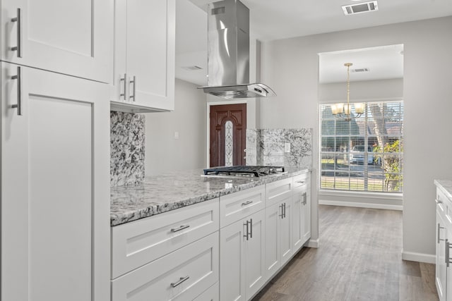 kitchen featuring white cabinets, decorative backsplash, wall chimney exhaust hood, and stainless steel gas cooktop