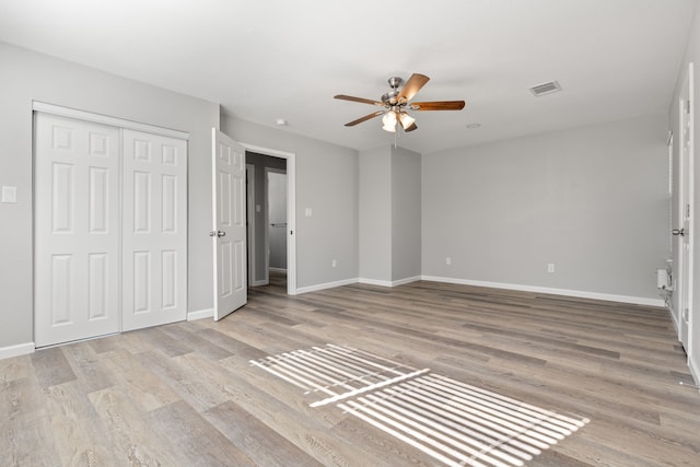 unfurnished bedroom featuring ceiling fan, light hardwood / wood-style floors, and a closet