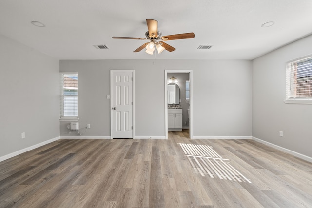 unfurnished bedroom with multiple windows, connected bathroom, light hardwood / wood-style flooring, and ceiling fan