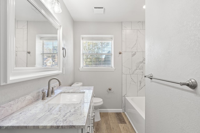 full bathroom with vanity, hardwood / wood-style flooring, toilet, and tiled shower / bath combo