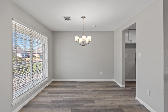 unfurnished dining area featuring dark hardwood / wood-style floors and a chandelier