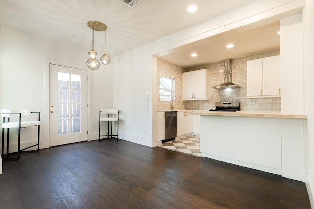 kitchen with kitchen peninsula, appliances with stainless steel finishes, wall chimney exhaust hood, decorative light fixtures, and white cabinets