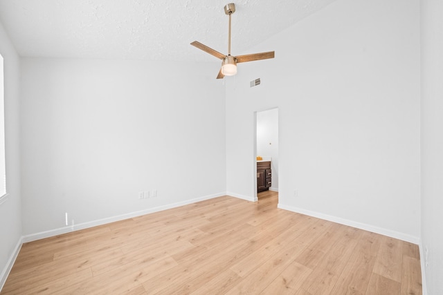 empty room featuring lofted ceiling, light wood-type flooring, ceiling fan, and a textured ceiling