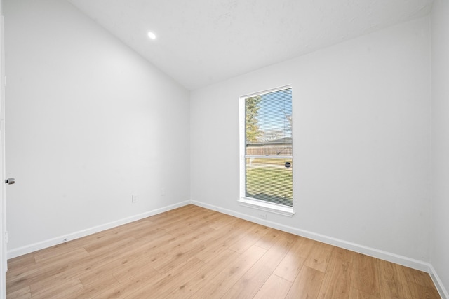 unfurnished room featuring vaulted ceiling and light hardwood / wood-style flooring