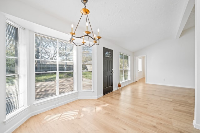 unfurnished dining area featuring light hardwood / wood-style flooring, an inviting chandelier, and vaulted ceiling