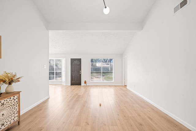 interior space featuring light wood-type flooring and vaulted ceiling with beams