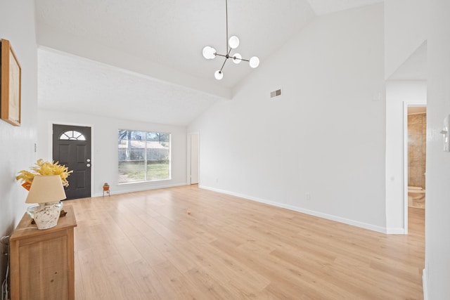 unfurnished living room featuring high vaulted ceiling, light hardwood / wood-style flooring, and a chandelier