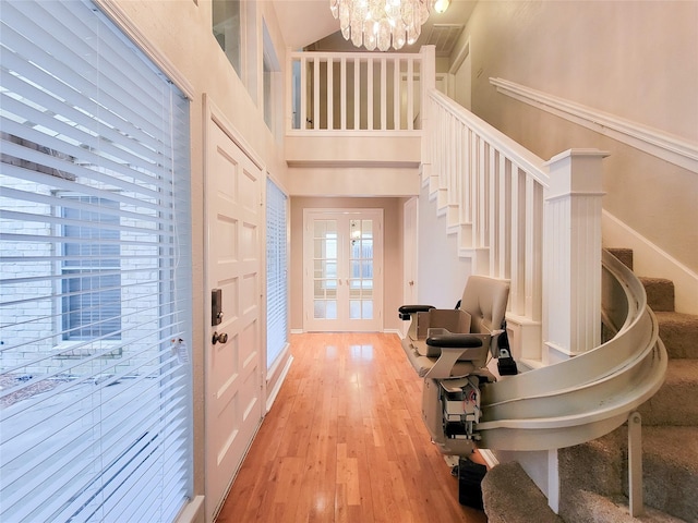 entryway with a chandelier, french doors, a towering ceiling, and light hardwood / wood-style floors