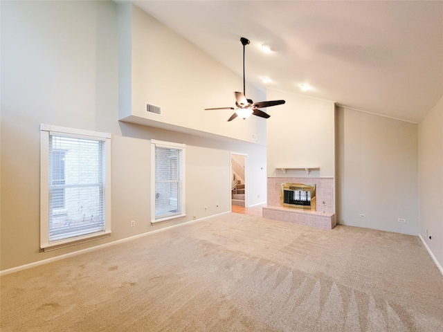 unfurnished living room featuring ceiling fan, light carpet, high vaulted ceiling, and a tiled fireplace