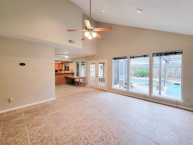 unfurnished living room with ceiling fan, french doors, and high vaulted ceiling