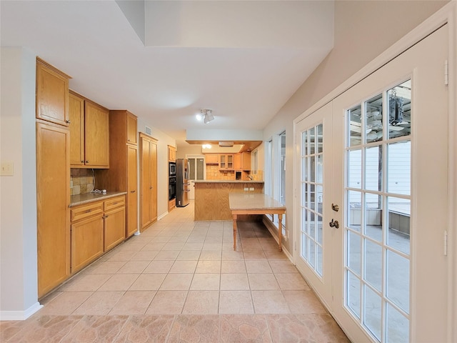 kitchen with a kitchen breakfast bar, backsplash, french doors, and light tile patterned flooring