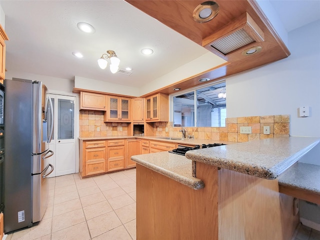 kitchen featuring kitchen peninsula, stainless steel refrigerator with ice dispenser, light stone countertops, tasteful backsplash, and light brown cabinetry