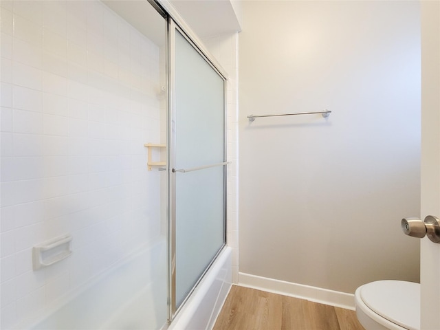 bathroom with hardwood / wood-style flooring, combined bath / shower with glass door, and toilet