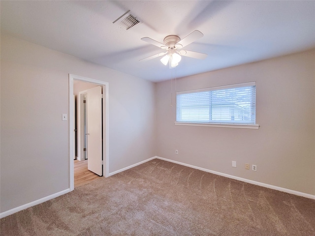 spare room with ceiling fan and light colored carpet