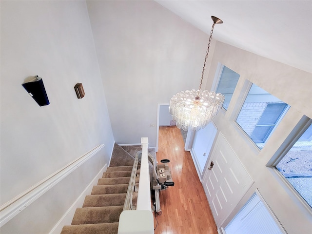 stairway featuring hardwood / wood-style floors, a towering ceiling, and a notable chandelier