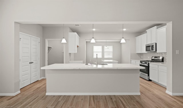 kitchen featuring sink, white cabinets, pendant lighting, and appliances with stainless steel finishes