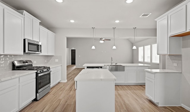 kitchen with decorative light fixtures, white cabinetry, sink, a center island, and stainless steel appliances