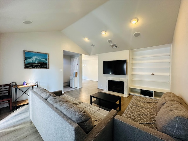 living room featuring hardwood / wood-style floors, a high end fireplace, and lofted ceiling