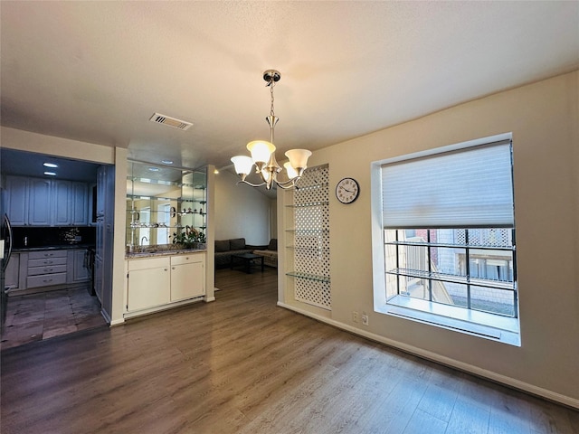 dining space featuring sink, dark hardwood / wood-style floors, and an inviting chandelier