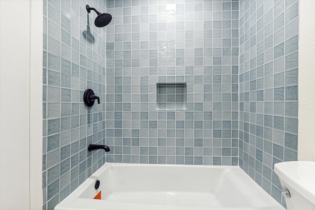 bathroom with tiled shower / bath combo and toilet