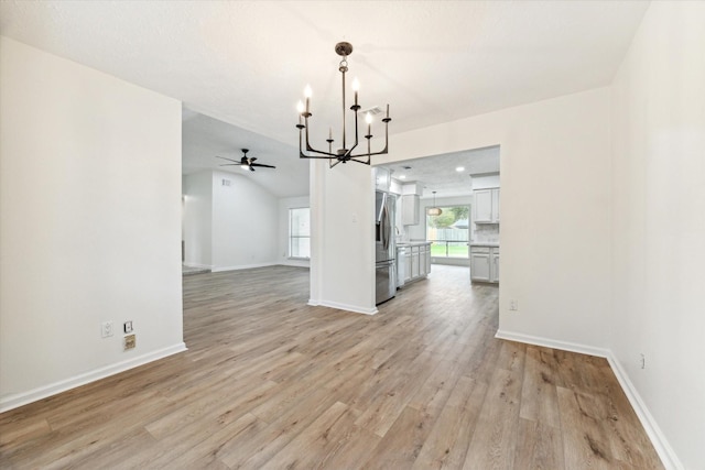 unfurnished dining area featuring vaulted ceiling, light hardwood / wood-style flooring, and ceiling fan with notable chandelier