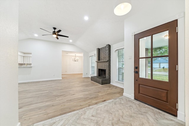 unfurnished living room featuring a textured ceiling, ceiling fan, lofted ceiling, and a fireplace