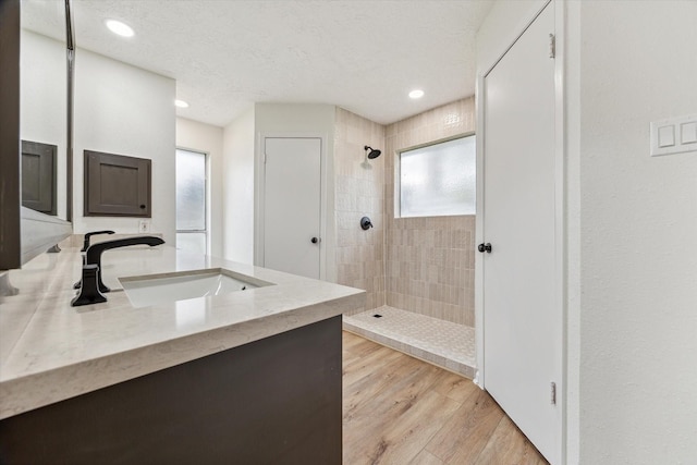 bathroom with a tile shower, vanity, a textured ceiling, and hardwood / wood-style flooring